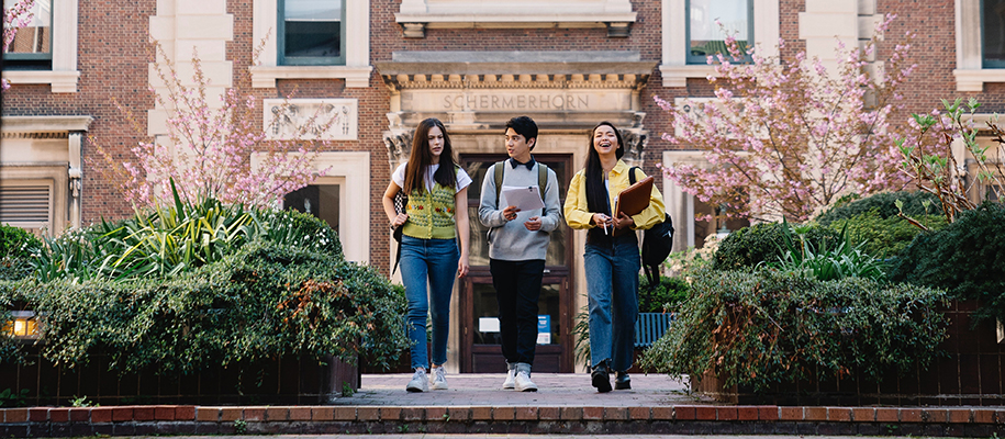 Asian male, Asian female, White female walking out of campus building